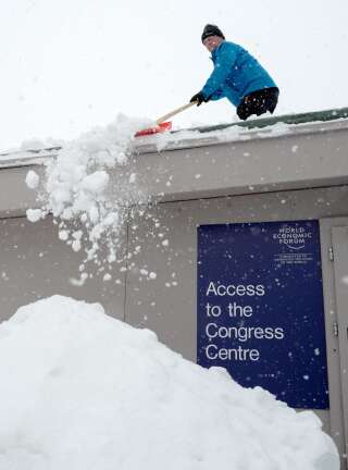 Un homme déblaie la neige d'un toit tout près du centre de congrès de Davos, le 21 janvier.