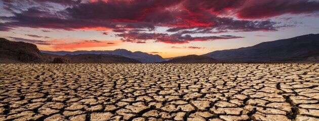 Sunset over cracked soil in the desert. Global warming