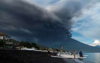 Indonesia's Mount Agung volcano erupts as fishermen pull a boat onto the beach in Amed, Bali, Indonesia, November 26, 2017. REUTERS/Petra Simkova