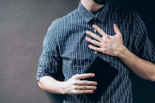 Plan serré sur un homme tenant une bible, la main sur sa poitrine.