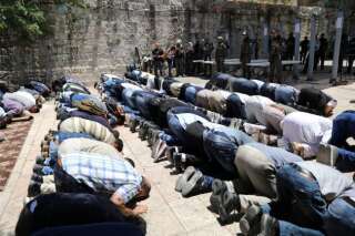 Des Palestiniens prient devant des policiers israéliens et les nouveaux portiques de sécurité, le 16 juillet à Jérusalem.