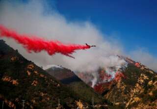 An aircraft drops flame retardant as firefighters battle the Woolsey Fire as it continues to burn in Malibu, California, U.S., November 11, 2018. REUTERS/Eric Thayer
