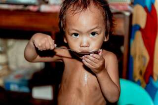 Un petit enfant sous-alimenté lèche la cuillère avec laquelle il vient de manger un peu de riz