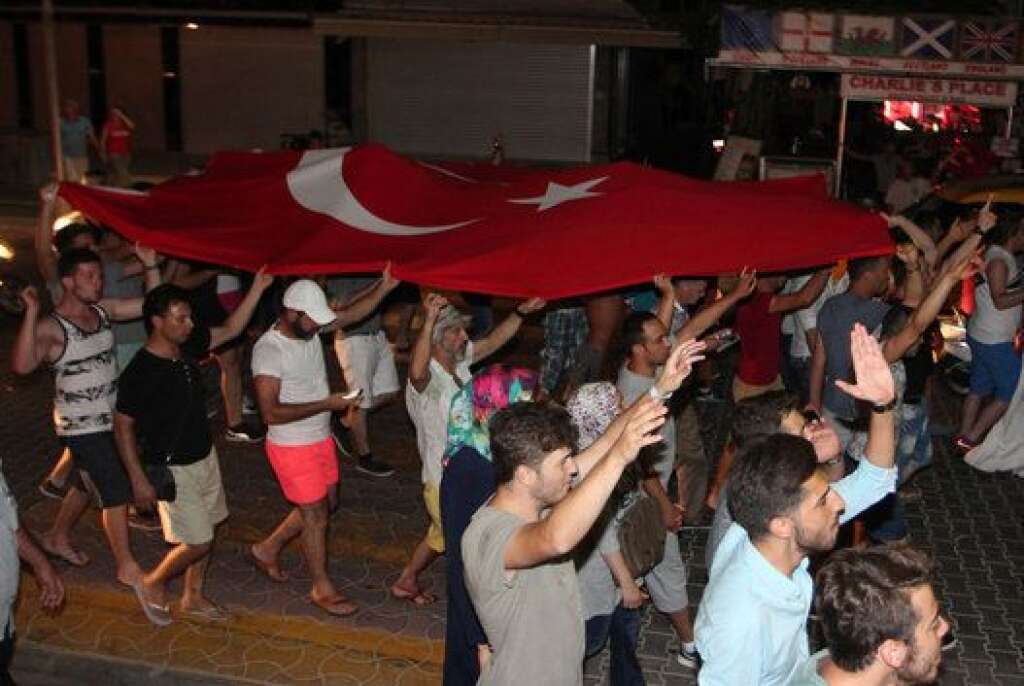 A crowd carries a Turkish flag in the resort town of Marmaris, Turkey July 16, 2016.    REUTERS/Kenan Gurbuz
