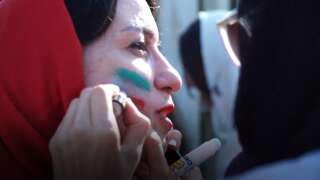 Des femmes se maquillent aux couleurs de l'Iran avant la rencontre Iran-Cambodge, jeudi 10 octobre.