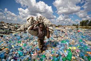Dans la décharge du bidonville de Dandora, à Nairobi, un homme progresse sur un monticule de déchetsen portant sur le dos un sac rempli de bouteilles en plastique qu’il compte revendre aux sociétés derecyclage après les avoir pesées