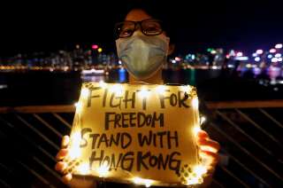 Hong Kong, le 23 août 2019. Une femme brandit une pancarte tandis que, le long de Tsim Sha Tsui et de la Hung Hom Promenade, des manifestants forment une chaîne humaine lors d’un rassemblement destiné à réclamer des réformes politiques.