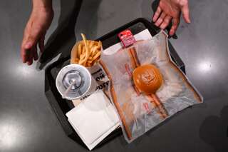 Sur le plateau, des frites, un burger, une boisson et une sauce Mcdo dont le nom et le logo ont été rayés de feutre noir.
