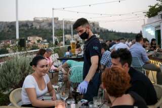 Un serveur dans un bar d’Athènes le 1er août. Depuis l’assouplissement du confinement, le nombre de cas de Coronavirus a explosé en Grèce.