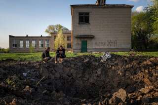 Des civils observent un cratère créé par une attaque à la roquette russe dans une cour d'école à Dobropillya, dans la région de Donetsk, dans l'est de l'Ukraine, jeudi 28 avril 2022.