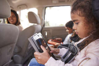 Mother turns to children using tablets in the back of the car