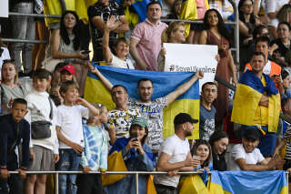 Kyiv supporters hold Ukrainian flags and a « SaveUkraine » placard during a friendly match between Belgian Royal Antwerp FC and Ukrainian FC Dynamo Kyiv, in Antwerp on July 15, 2022.TOM GOYVAERTS / BELGA / AFP