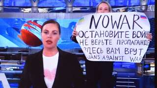 A woman looks at a computer screen watching a dissenting Russian Channel One employee entering Ostankino on-air TV studio during Russia's most-watched evening news broadcast, holding up a poster which reads as 