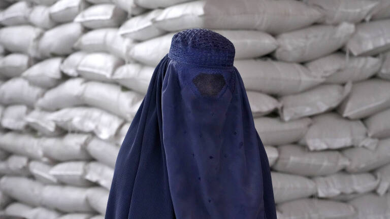 An Afghan woman waits to receive a food ration distributed by a South Korea humanitarian aid group, in Kabul, Afghanistan, Tuesday, May 10, 2022. (AP Photo/Ebrahim Noroozi)