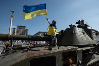 KYIV, UKRAINE - AUGUST 21: A boy wrapped in Ukrainian national flag holds a Ukrainian national flag as he stands on top of a Russian military vehicles displayed in the downtown area on August 21, 2022 in Kyiv, Ukraine. On August 24, Ukraine celebrates its 1991 declaration of independence from the USSR. Wednesday also marks six months since Russia launched its large-scale invasion of Ukraine. Scores of burnt-out Russian military vehicles were left around Kyiv after its failed attempt to seize the Ukrainian capital in the first month of the war. (Photo by Alexey Furman/Getty Images)