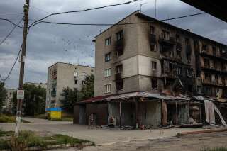 A man walks down a street next to burnt residential buildings due to constant shelling in Siversk, Donetsk region on August 20, 2022, amid the Russian invasion of Ukraine.  (Photo by ANATOLII STEPANOV / AFP)