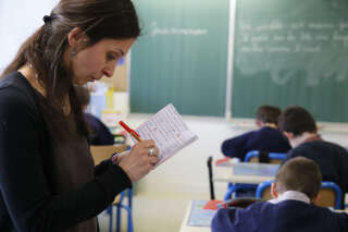 Primary school in France. Schoolteacher marking a notebook.