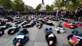 People hold placards reading names of women as they lay on the ground of place de la Republique, in Paris, during a 