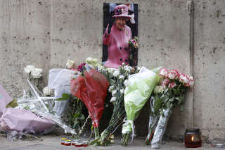 Photographie prise le 9 septembre 2022 montrant un portrait de la reine Elizabeth II et des fleurs disposées à l’ambassade britannique à Paris, un jour après la mort de la reine à l’âge de 96 ans.