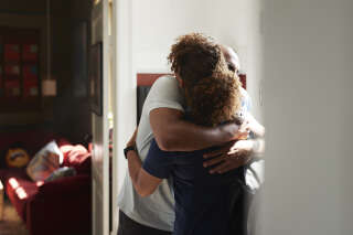 Rear view of female caregiver embracing while greeting man at home