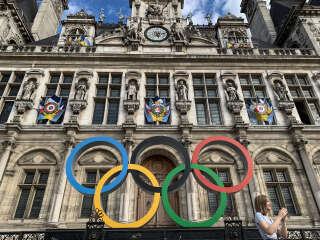 A woman poses in front of the Olympic Rings at the Hotel De Ville in Paris on September 2, 2022, the city that will host the 2024 Olympic and Paralympic Games. (Photo by Behrouz MEHRI / AFP)