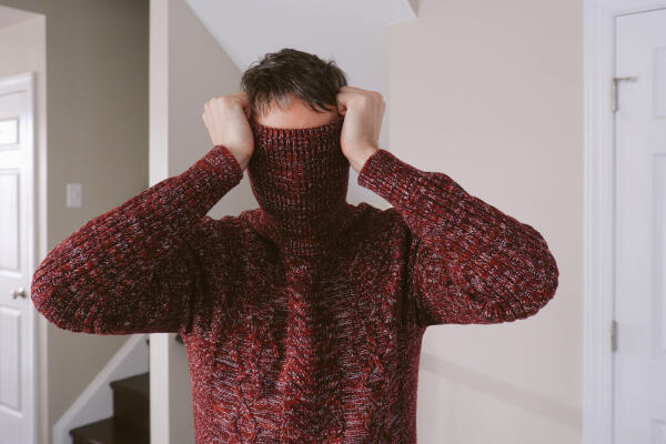 Close-up of unrecognizable man covering face with sweater