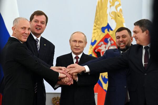 (L-R) The Moscow-appointed heads of Kherson region Vladimir Saldo and Zaporizhzhia region Yevgeny Balitsky, Russian President Vladimir Putin, Donetsk separatist leader Denis Pushilin and Lugansk separatist leader Leonid Pasechnik join hands after signing treaties formally annexing four regions of Ukraine Russian troops occupy, at the Kremlin in Moscow on September 30, 2022. (Photo by Grigory SYSOYEV / SPUTNIK / AFP)