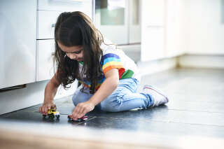 Girl (4-5) playing toy cars in kitchen