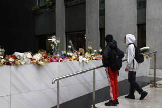 Teenagers look at the bouquets of flowers displayed at the entrance of the building where Lola, a 12 year-old schoolgirl who was found dead in a trunk in the 19th district on October 14, 2022, lived, in Paris on October 17, 2022. (Photo by Geoffroy Van der Hasselt / AFP)