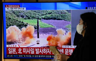 A woman walks past a television screen showing a news broadcast with file footage of a North Korean missile test, at a railway station in Seoul on November 3, 2022. - North Korea fired one long-range and two short-range ballistic missiles on November 3, Seoul's military said, with one prompting warnings for residents of a South Korean island and people in parts of northern Japan to seek shelter. (Photo by Jung Yeon-je / AFP)
