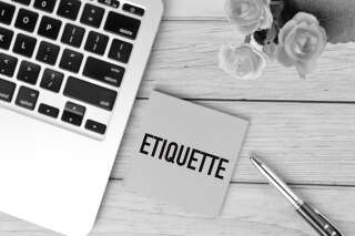 Black and white picture of laptop, pen, flowers and memo note written with ETIQUETTE. Business and education concept