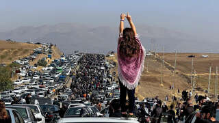 This UGC image posted on Twitter reportedly on October 26, 2022 shows an unveiled woman standing on top of a vehicle as thousands make their way towards Aichi cemetery in Saqez, Mahsa Amini's home town in the western Iranian province of Kurdistan, to mark 40 days since her death, defying heightened security measures as part of a bloody crackdown on women-led protests. - A wave of unrest has rocked Iran since 22-year-old Amini died on September 16 following her arrest by the morality police in Tehran for allegedly breaching the country's strict rules on hijab headscarves and modest clothing. (Photo by UGC / AFP) / === RESTRICTED TO EDITORIAL USE - MANDATORY CREDIT 
