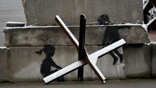 Dans la peinture murale de Banksy créée à Kyiv, deux enfants semblent marcher sur des défenses antichars.