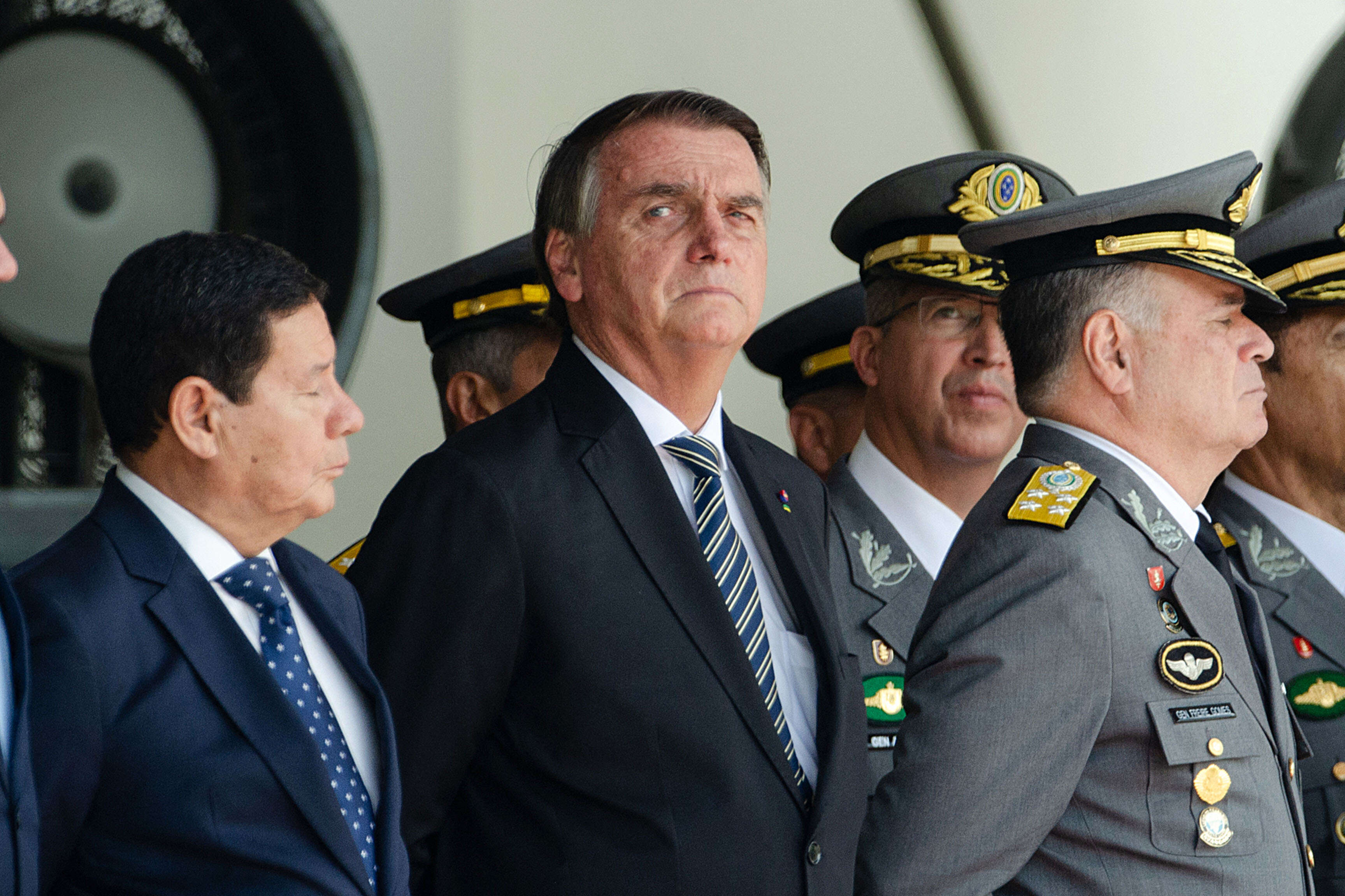 Brazilian President Jair Bolsonaro (C) attends next his Vice President Hamilton Mourao (L) and Commander of the Army General Marco Antonio Freire Gomes a graduation ceremony for cadets at the Agulhas Negras Military Academy in Resende, Rio de Janeiro State, Brazil, on November 26, 2022. - Bolsonaro has returned to a public event after more than three weeks without a public appearance following his election defeat by Luiz Inacio Lula da Silva. (Photo by TÉRCIO TEIXEIRA / AFP)