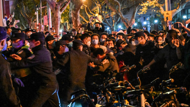 Police and guards arrest a man during some clashes in Shanghai on November 27, 2022, where protests against China's zero-Covid policy took place the night before following a deadly fire in Urumqi, the capital of the Xinjiang region. (Photo by HECTOR RETAMAL / AFP)