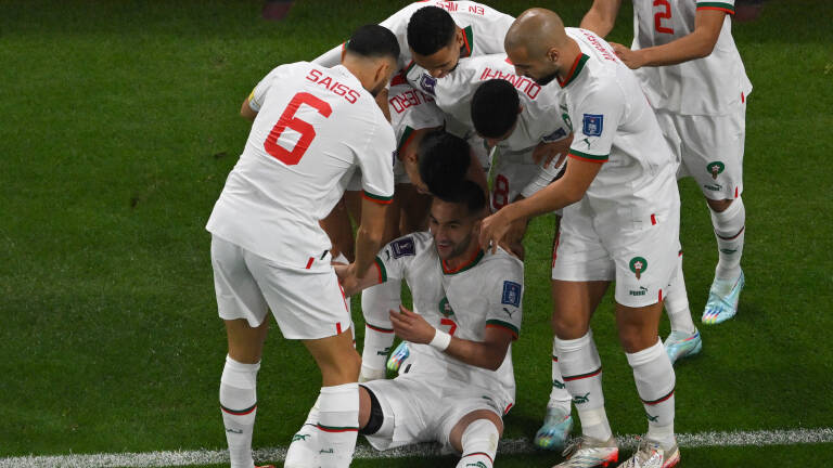 Morocco's midfielder #07 Hakim Ziyech (bottom) celebrates with teammates after he scored his team's first goal  during the Qatar 2022 World Cup Group F football match between Canada and Morocco at the Al-Thumama Stadium in Doha on December 1, 2022. (Photo by Antonin THUILLIER / AFP)