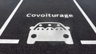 A parking space reserved for motor vehicles for carpooling (covoiturage in french). Photograph taken in a street in the city center in Evian-Les-Bains, Haute-Savoie, France. White paint on dark gray asphalt. Clean surface. Sunlight.