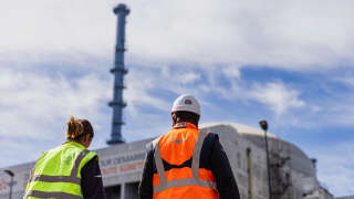 Des ouvriers passent devant un bâtiment du réacteur nucléaire de troisième génération du projet de réacteur pressurisé européen (EPR) de Flamanville, en Normandie, le 14 juin 2022. - EDF doit démarrer l’EPR de Flamanville en 2023 après d’innombrables retards et déboires. (Photo de Sameer Al-DOUMY / AFP)