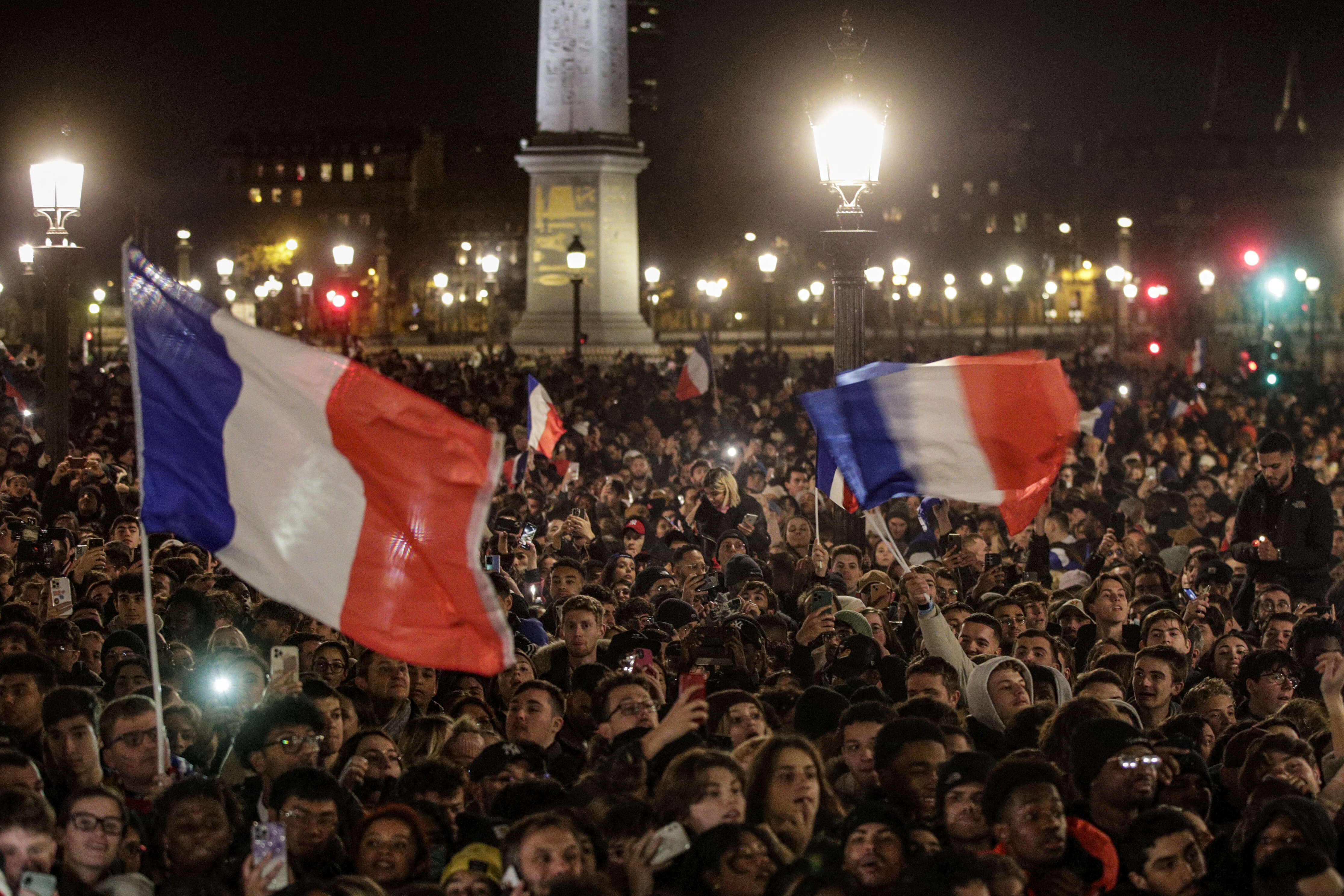 Fans wave French flags as they wait at the Place de la Concorde for the arrival of the French national football team at the Hotel de Crillon, a day after the Qatar 2022 World Cup final match against Argentina, in central Paris on December 19, 2022. (Photo by GEOFFROY VAN DER HASSELT / AFP)