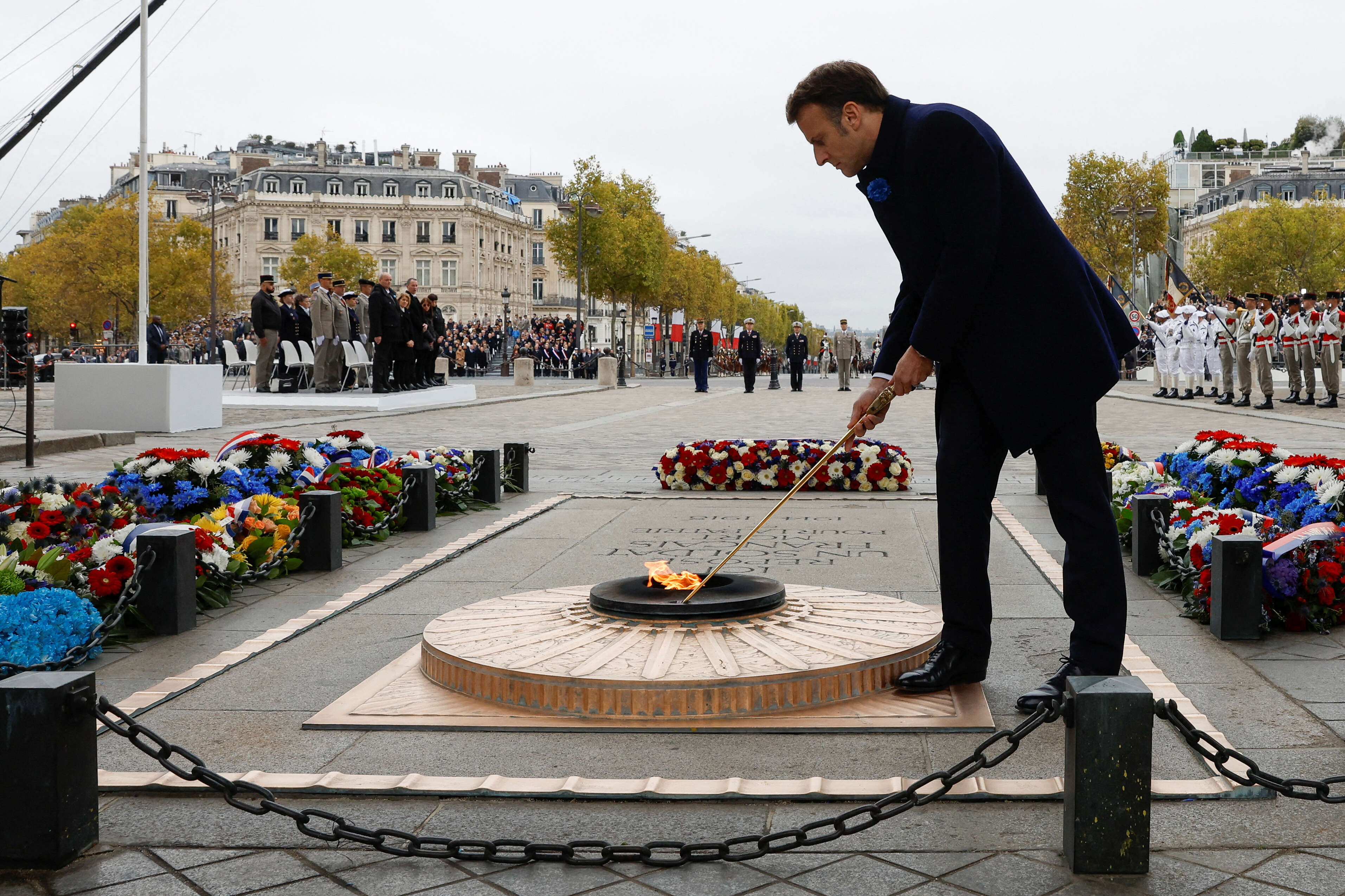 French President Emmanuel Macron adjusts the flame of the Tomb of the Unknown Soldier during a ceremony at the Arc de Triomphe in Paris on November 11, 2022, as part of commemorations marking the 104th anniversary of the November 11, 1918 Armistice, ending World War I (WWI). (Photo by GONZALO FUENTES / POOL / AFP)