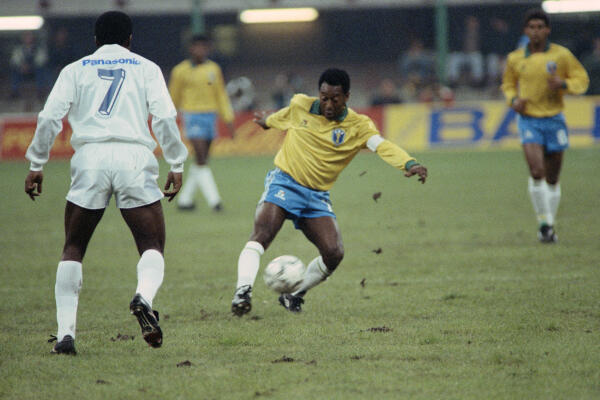 Former Brazilian soccer star, Edson Arantes do Nascimento, known as Pelé (L), plays the ball during a friendly soccer match opposing Brazil to world soccer star to celebrate Pele's fiftieth birtday in Milan on October 31, 1990. (Photo by Gerard MALIE / AFP)