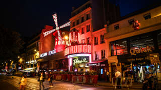 Des badauds passent devant le Moulin Rouge à Paris le 8 septembre 2021, deux jours avant la réouverture du cabaret après 18 mois de fermeture en raison de la pandémie de COVID-19. - Fermés depuis un an et demi en raison de la pandémie, le Moulin Rouge et le Lido, emblèmes des folles nuits parisiennes depuis 1889, rouvrent enfin leurs portes. (Photo de Christophe ARCHAMBAULT / AFP)