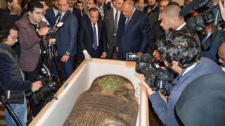 Egypt's Foreign Minister Sameh Shoukry (C-R) and the head of the Supreme Council of Antiquities Mostafa Waziri (C-L) are surrounded by journalists as they inspect an ancient Egyptian wooden sarcophagus being handed over and which was formerly displayed at Houston Museum of Natural Sciences after having been looted and smuggled years prior, at the foreign ministry headquarters in the capital Cairo on January 2, 2023. - Egypt announced on January 2 the recovery of a sarcophagus lid dating back nearly 2,700 years that it said had been smuggled out and put on display at a museum in the United States. Foreign Minister Sameh Shoukry announced the recovery of the artefact, known as the 