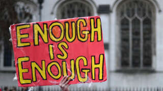A demonstrator holds a sign reading 'Enough is Enough' as they take part in a rally organised by the Communication Workers Union (CWU), in support of Royal Mail postal workers who are on strike, in Parliament Square in central London on December 9, 2022. - The Communication Workers Union said postal workers had voted overwhelmingly for more strikes this year and next, affecting deliveries in the run-up to Christmas and opening hours at post offices. Formerly state-owned Royal Mail recently announced it would axe up to 10,000 jobs, blaming the move partly on staff strikes that contributed to a first-half loss. (Photo by Daniel LEAL / AFP)