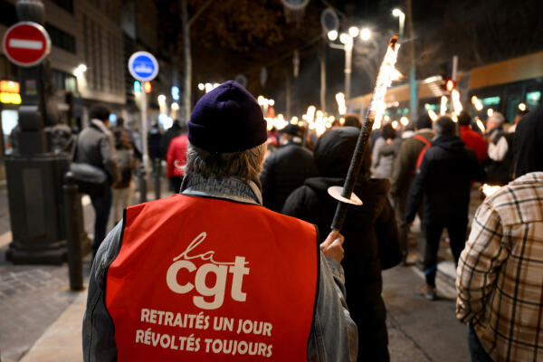 Protesters take part in a torch-lit march called by the CGT workers' union to protest the French government's pensions reform plan, on the Canebiere in Marseille, southeastern France, on January 17, 2023. - France is to face strikes across different sectors on January 19, 2023, as workers join a nationwide strike against a widely unpopular pension reform plan. The suggested changes, still to be debated in parliament, would raise the retirement age from 62 to 64 and increase contributions required for a full pension. (Photo by Nicolas TUCAT / AFP)