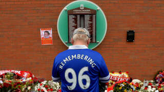 Sur cette photo d’archive prise le 15 avril 2015, un supporter d’Everton se tient devant le mémorial temporaire de Hillsborough, à l’occasion du 26e anniversaire de la catastrophe de Hillsborough.
