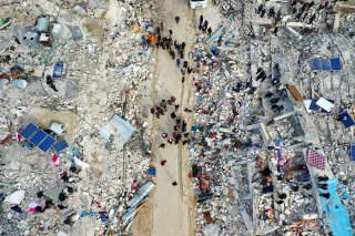 This aerial view shows residents searching for victims and survivors amidst the rubble of collapsed buildings following an earthquake in the village of Besnia near the twon of Harim, in Syria's rebel-held noryhwestern Idlib province on the border with Turkey, on February 6, 2022. - Hundreds have been reportedly killed in north Syria after a 7.8-magnitude earthquake that originated in Turkey and was felt across neighbouring countries. (Photo by Omar HAJ KADOUR / AFP)