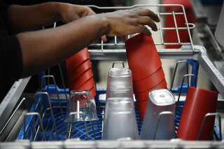 An employee removes reusable dishes and containers from a dishwasher at a McDonald's restaurant in Levallois-Perret, near Paris, on December 20, 2022. - From January 1, 2023, within the framework of the anti-waste law, fast food restaurants must use reusable dishes for on-site orders. (Photo by JULIEN DE ROSA / AFP)