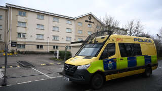 Un fourgon de police est vu garé devant les portes fermées de l’hôtel Suites à Kowlsey, près de Liverpool, dans le nord-ouest de l’Angleterre, le 11 février 2023.