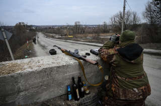 TOPSHOT - An Ukrainian serviceman looks through binoculars towards the town of Stoyanka at a checkpoint before the last bridge on the road that connects Stoyanka with Kyiv, on March 6, 2022. (Photo by ARIS MESSINIS / AFP)